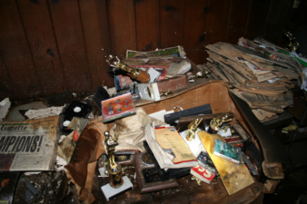 Several trophies, newspapers, video tapes and other items were stacked on this desk inside the office.