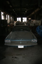 An old car with a thick layer of dust sat inside the building.
