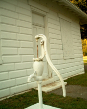 A water pump was just outside of the small building.
