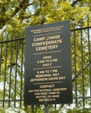 A newer sign with the hours of operation and contact information for the cemetery.