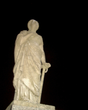 A statue of a woman leaning on a sword, looking toward the heavens.
