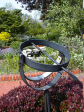 A sundial like sculpture at the center of the garden.
