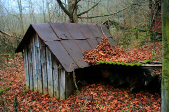 The chicken coop with the red house in the background.