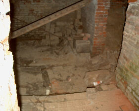 The basement floor was littered with bricks, dust and dirt. The stairway that led to the basement was crumbling and covered by a large plank of wood.