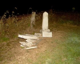 A pile of broken tombstones along the fence.