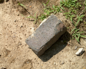 A single red brick on the ground in the rest stop parking area.