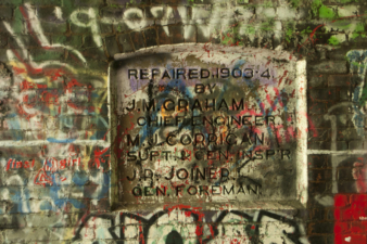 The rededication plaque as it appeared in 2014, still surrounded by graffiti.
