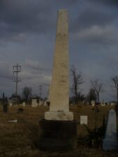 The tombstone of John Magers with an ominous-looking sky in the background.