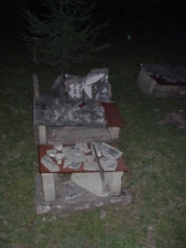 The broken tombstone pieces lay atop small table-like structures.