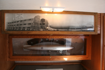 A model of the USS Shenandoah below a photo of the airship in Lakehurst.