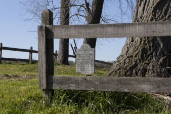 Looking through the wood fence to the cemetery's memorial stone.