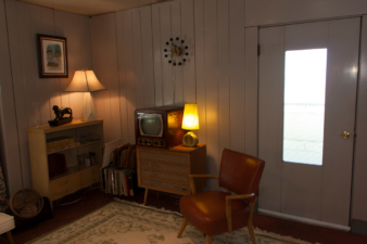 Adjacent to the home's front door was a chair, shelf with period TV, and a bookshelf.