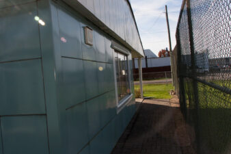The front, north-facing side of the Lustron home was against a fence originally installed for volleyball court.