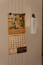 A 1947 calendar and thermometer hung on the wall via magnets between the kitchen and dining room.